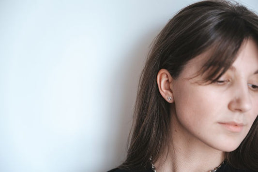 close-up of a woman's ear wearing simple gold stud earrings, natural light, real and unstyled