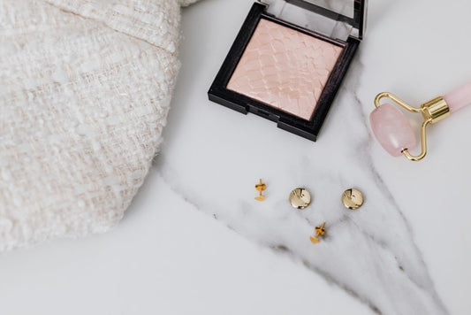 Gold stud earrings resting in a small ceramic dish on a wooden nightstand