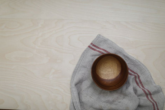 overhead flat lay of silver jewelry cleaning supplies soft cloth bowl of water on warm neutral surface