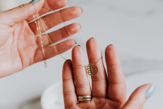 Macro close-up of a gold necklace being turned over in hand, warm natural light, minimal styling