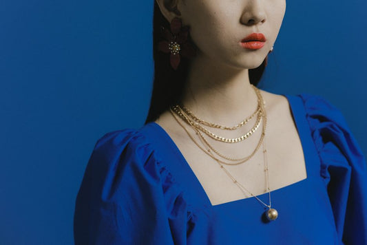 Gold vermeil pendant necklace next to a solid gold chain on a neutral surface