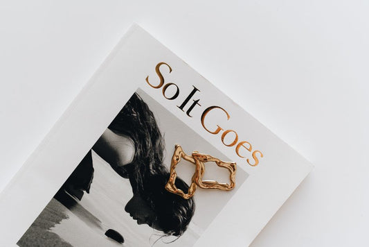 Hero — Journey Flow Hoops or Resilience Interlock Studs on a real person, warm natural light, ivory background