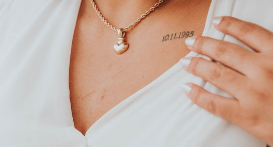 Woman wearing gold pendant necklace with white collared shirt at desk