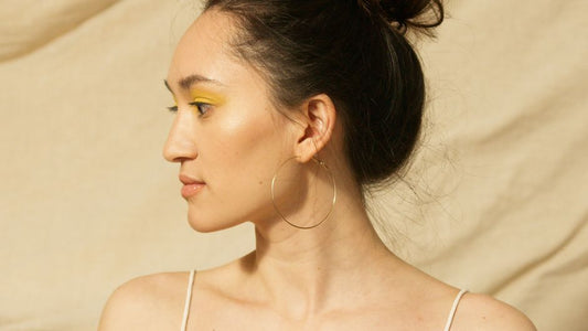 Natural-light close-up of a woman's ear wearing the Journey Flow Hoops, soft and real, not styled