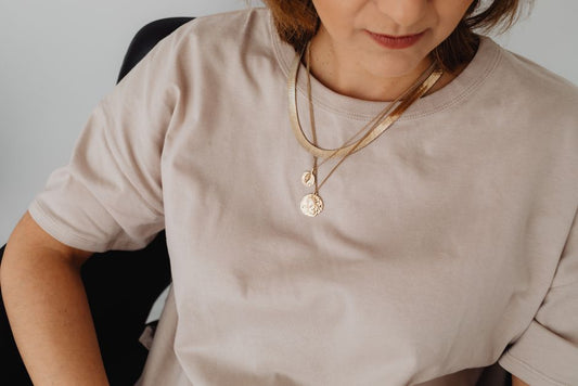 Real-person minimal two-necklace layer worn on the body, V-neck or scoop, warm natural light