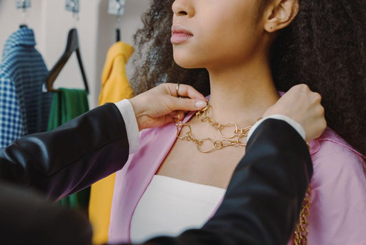Close up gold chain necklace resting on woman's collarbone neutral background