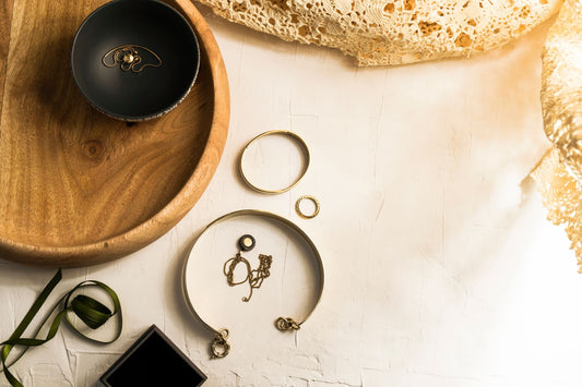Gold hoop earrings and a fine gold pendant necklace laid on linen in daylight